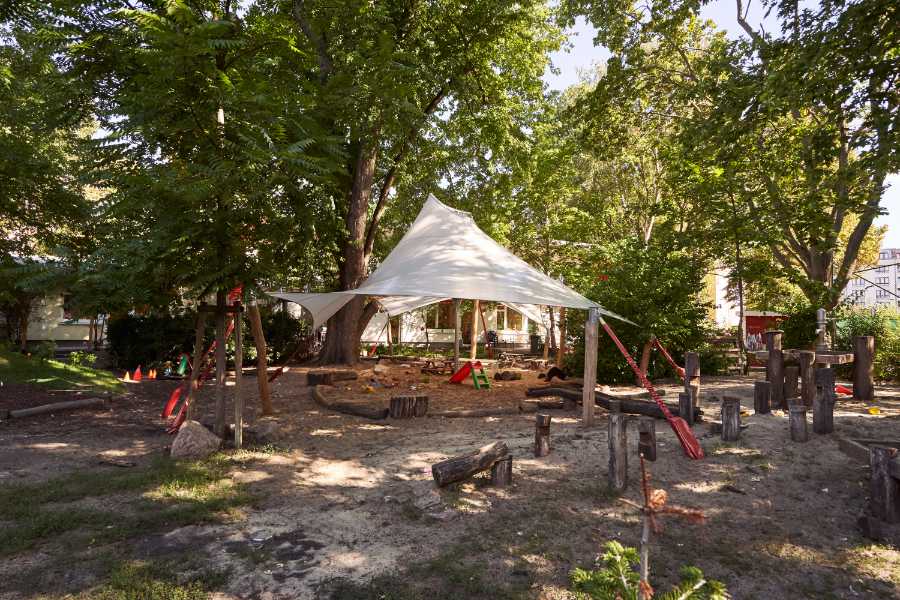 Stretchzelt kaufen von STOFFDACH Berlin | Ein wunderschönes Sonnensegel, dessen Membran in sich verdreht ist, überdacht den Sandkasten einer Kita in Berlin.