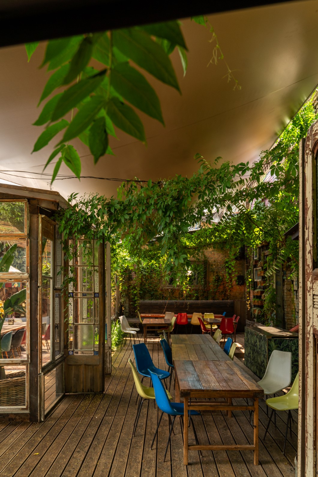 Ein Rollsegel über Stühlen und Tischen im Außenbereich des Treehouses in Berlin.