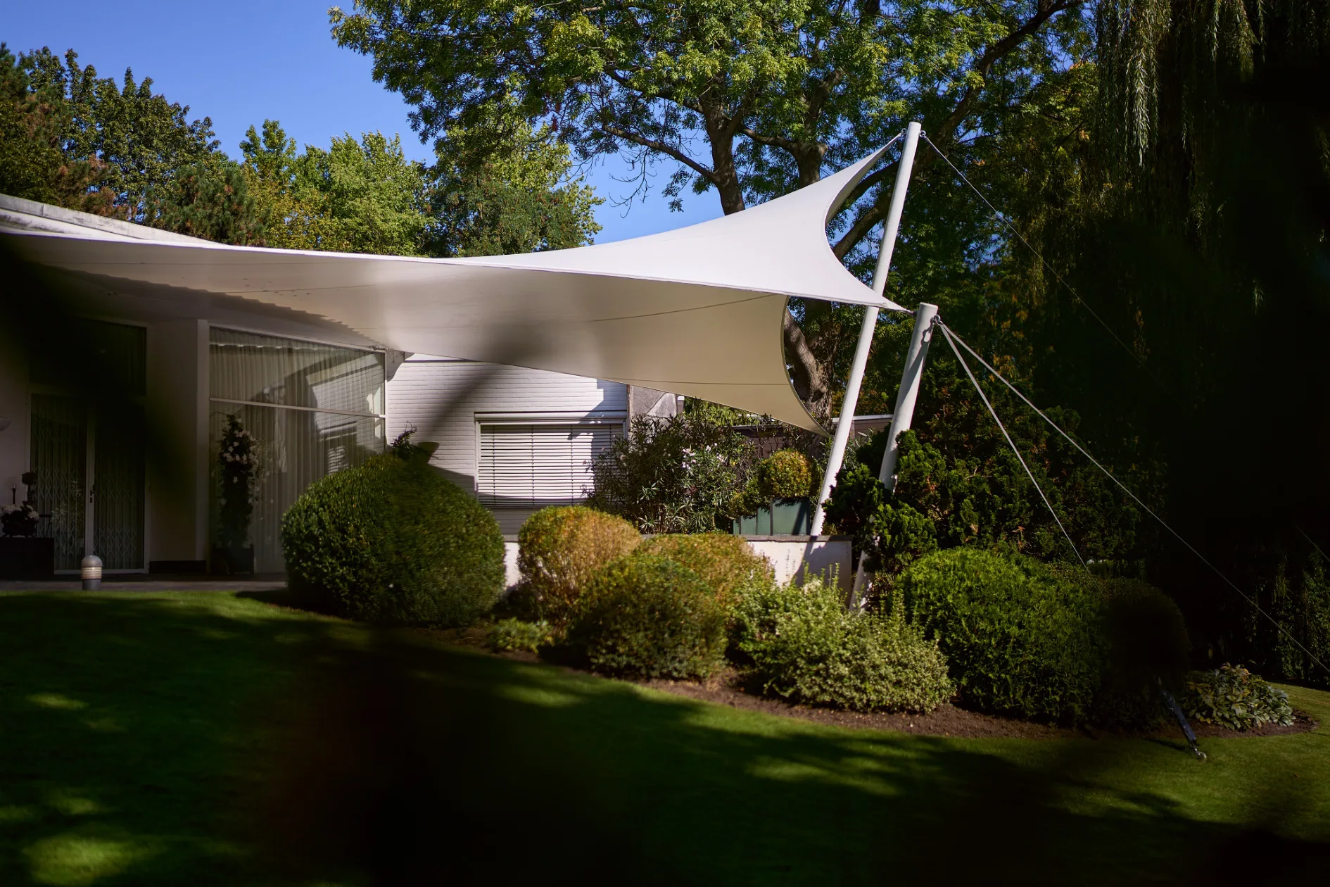 Ein Sonnensegel überspannt die private Terrasse einer Villa und fügt sich organisch in den Garten ein.